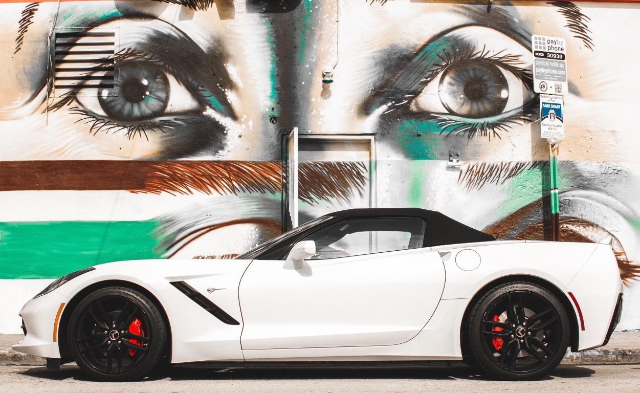 white corvette in front of graffiti