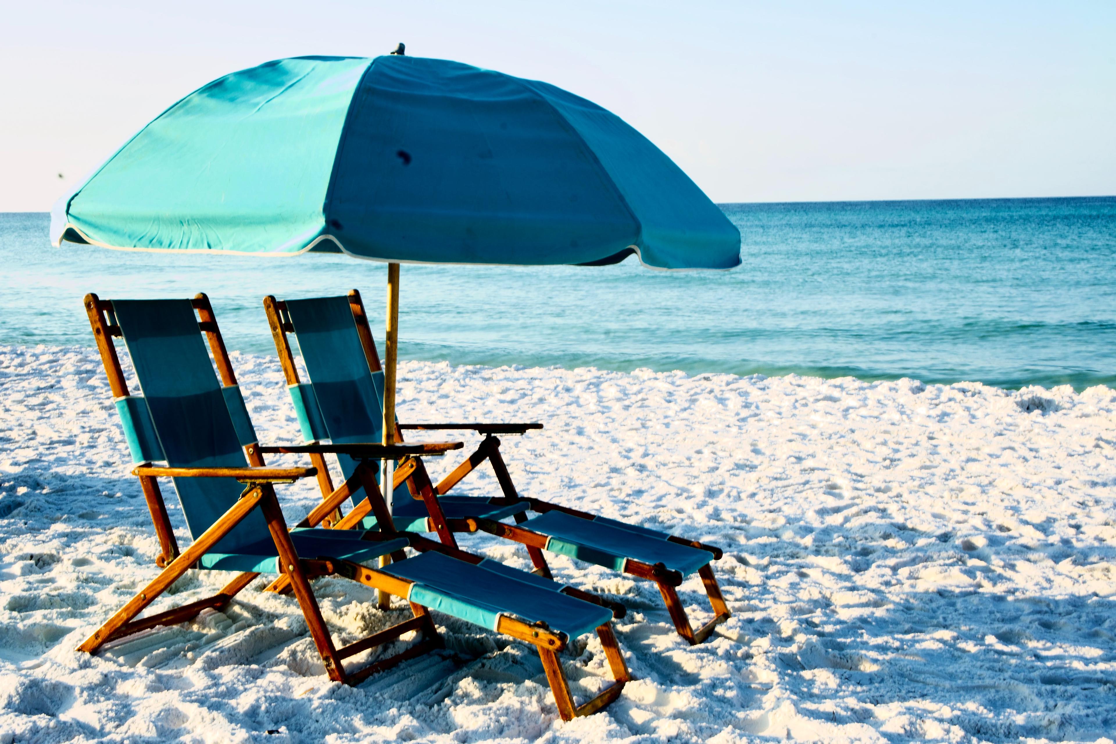 A pair of beach chairs next to the ocean on a beach in Destin Florida. 