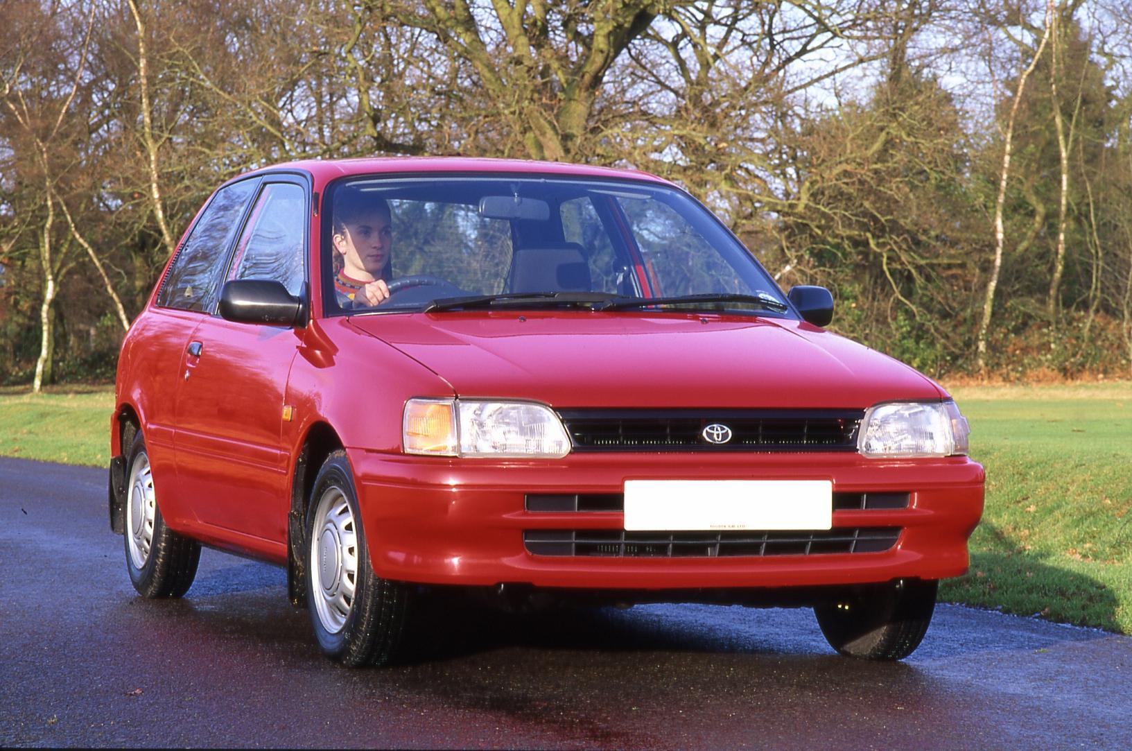 A red 1990 Toyota Starlet driving down the street