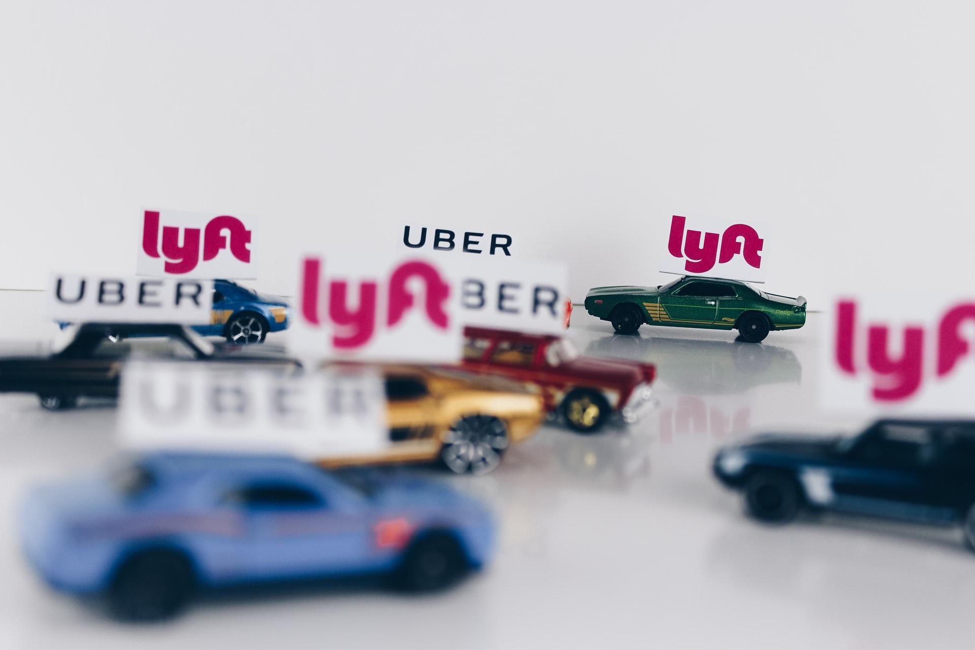 Toy cars with Uber and Lyft signs placed on top of them.