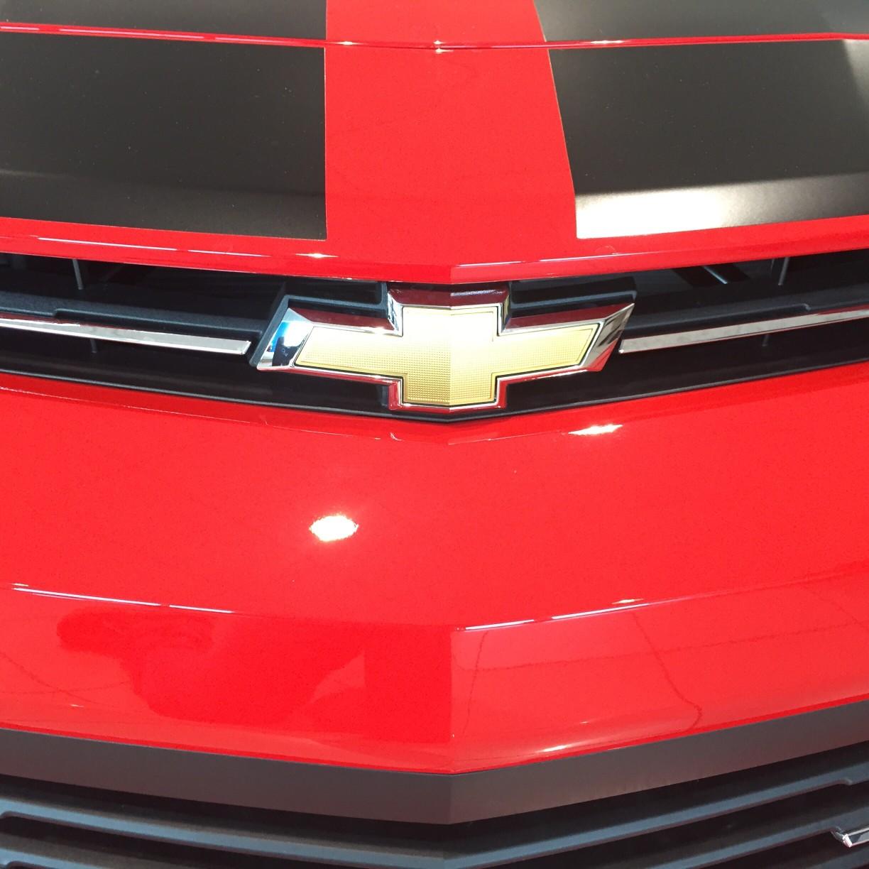 A closeup of the front of a red Camaro 
