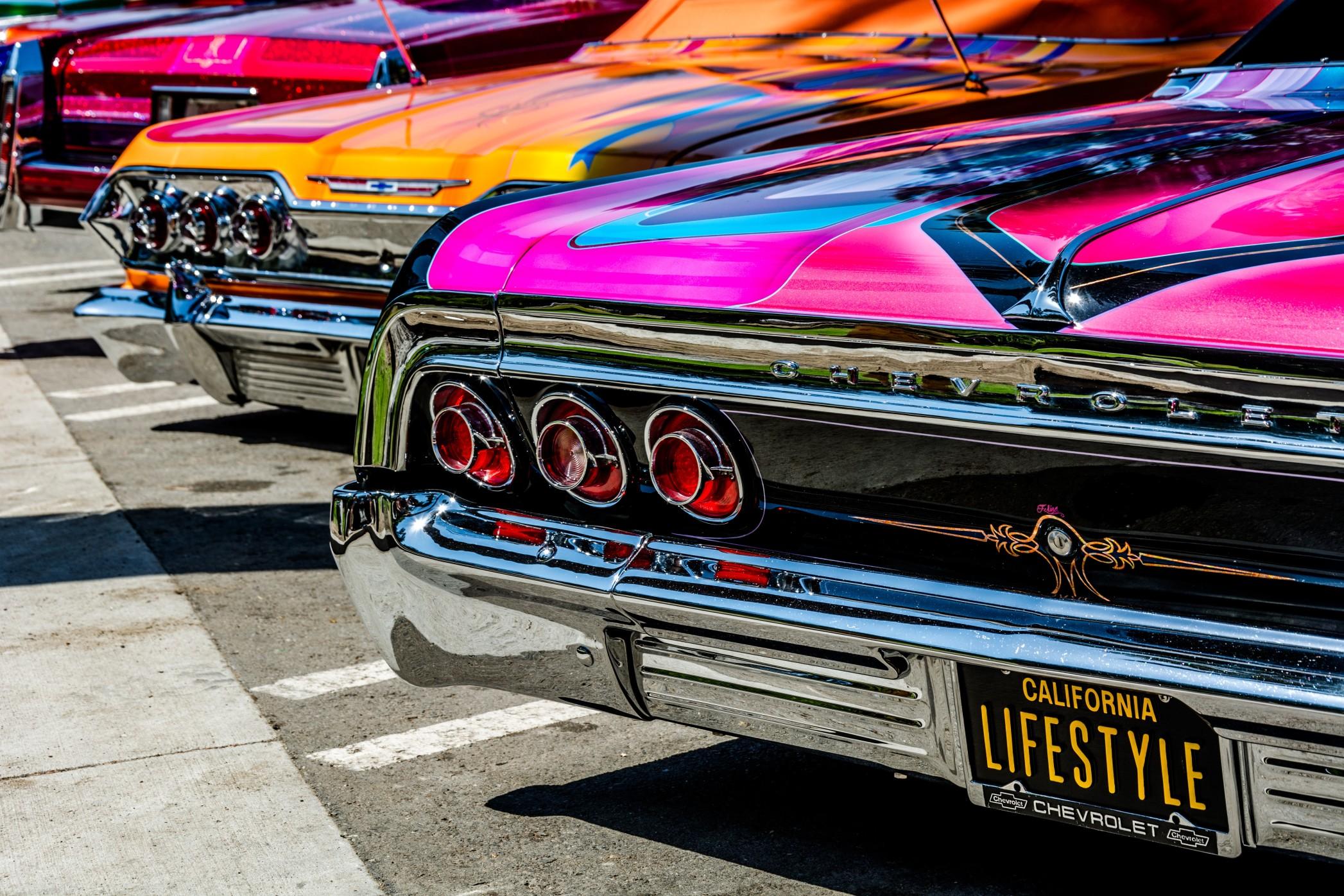 View of three colorful Chevy lowriders from the back 