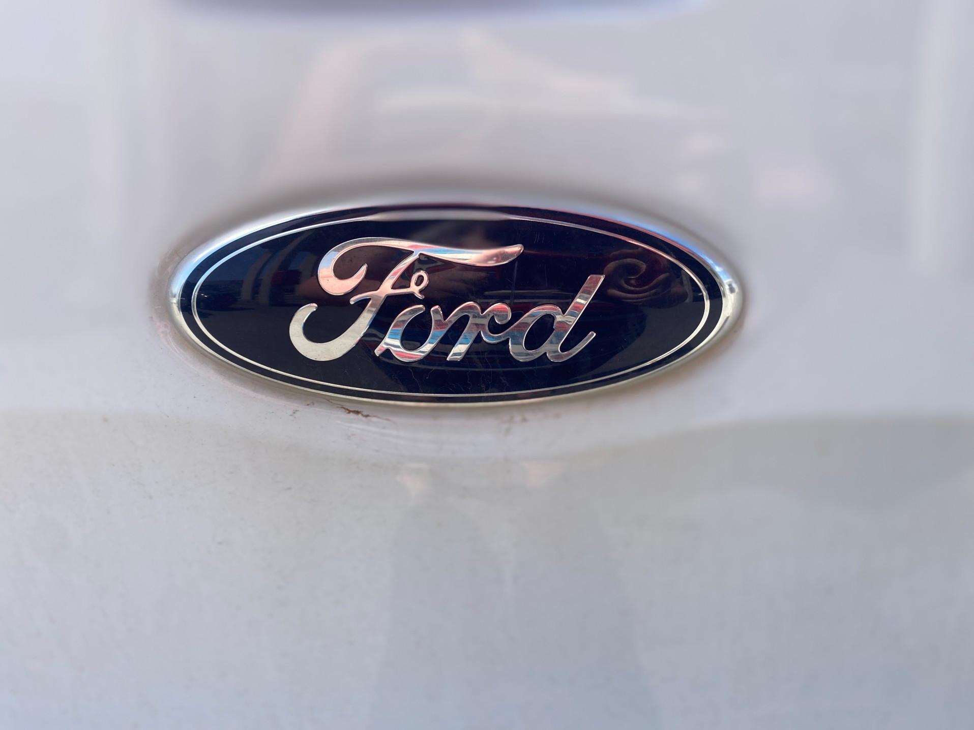 A Ford logo on the back of a white car.