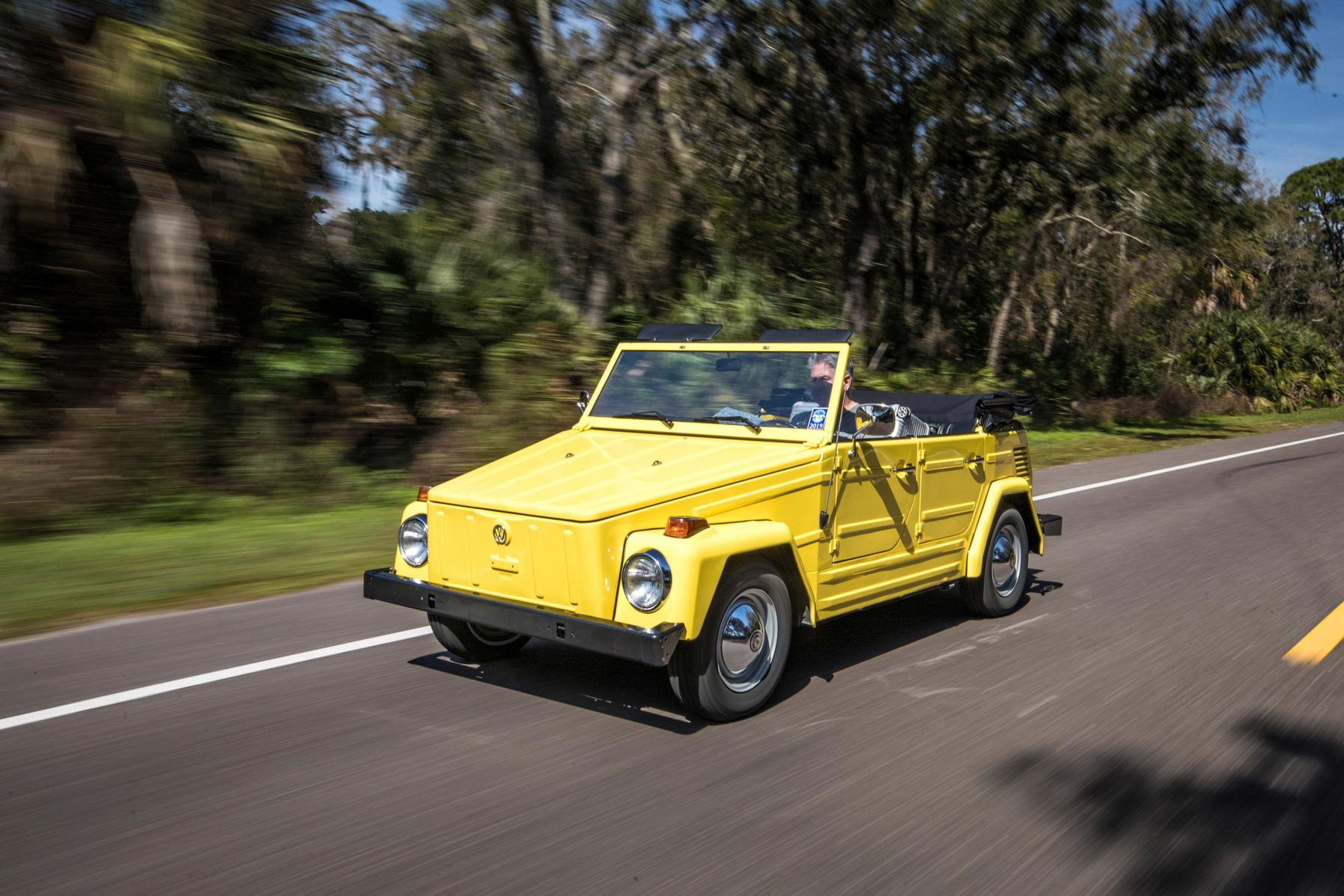 A yellow Volkswagen Thing driving down a street