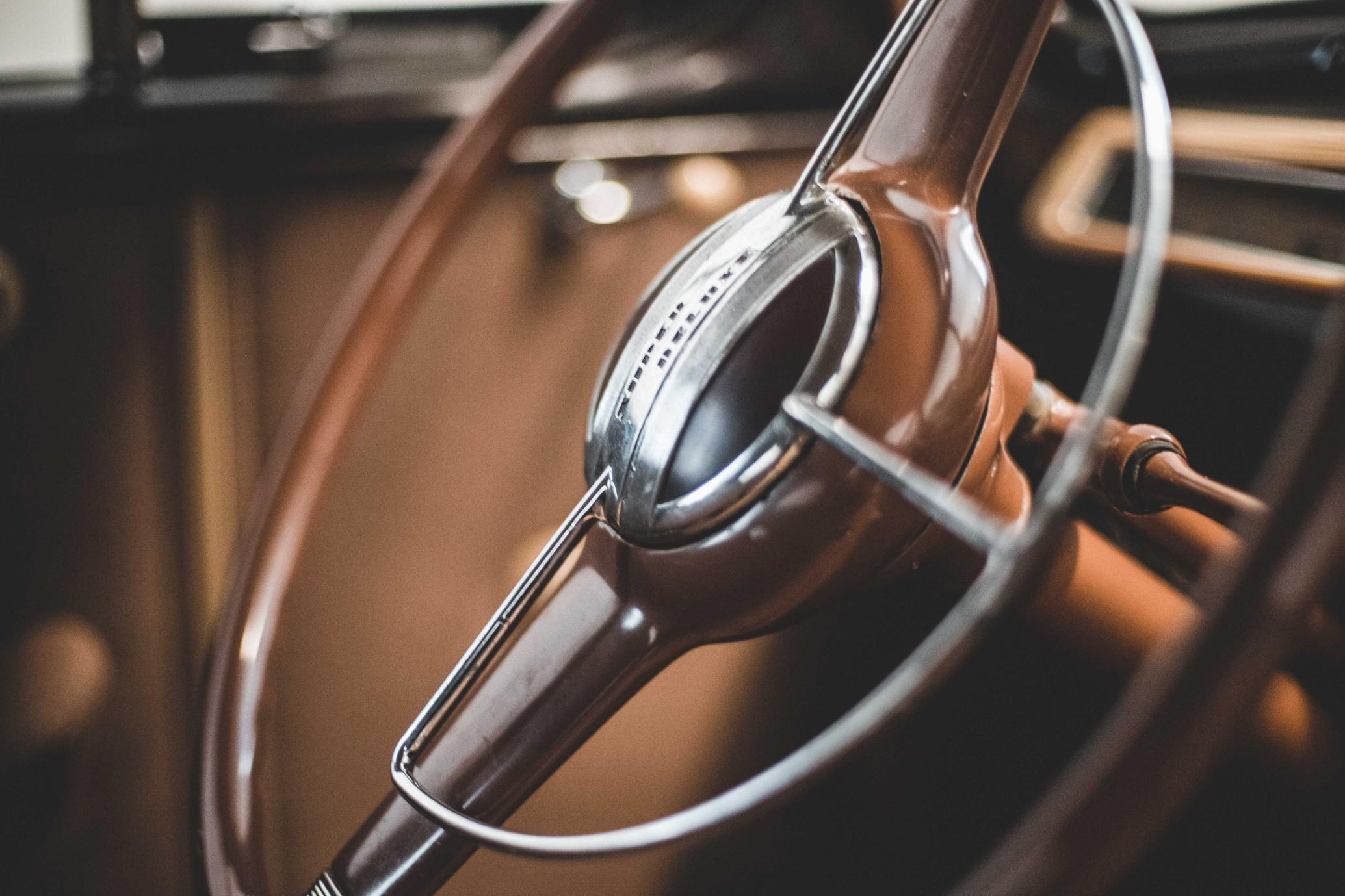 A close-up shot of the steering wheel on a classic car.