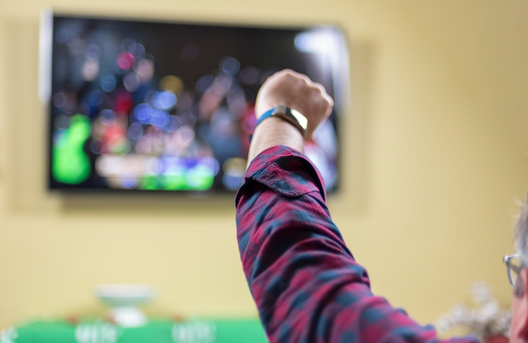 man in front of a TV, cheering for his team