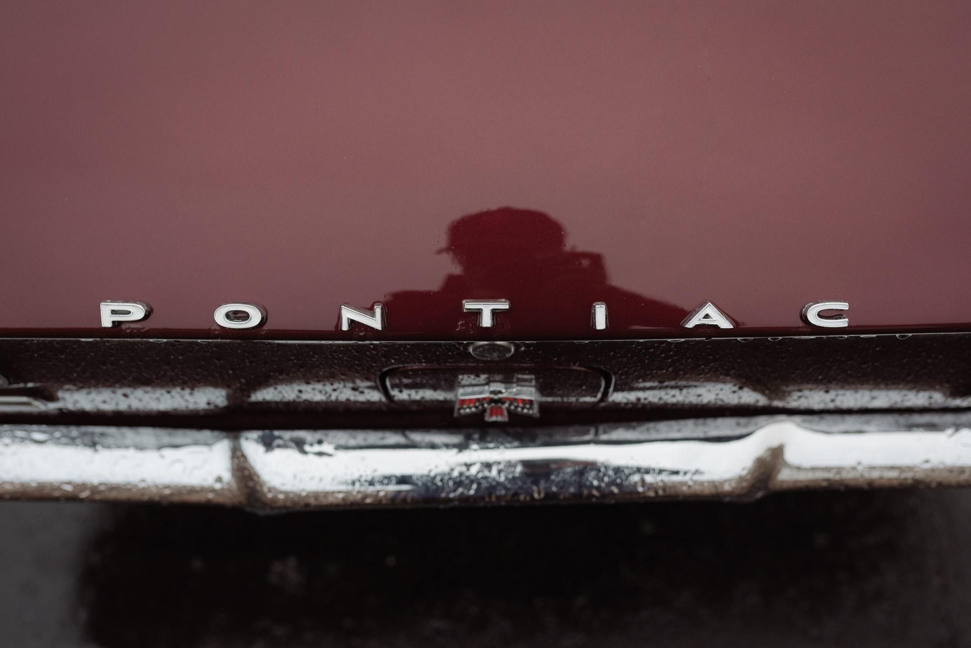 Burgundy Pontiac hood with silver nameplate viewed from above