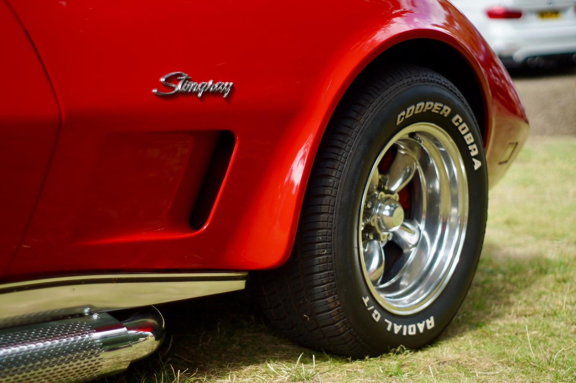 Lower body and wheel of a red Corvette with a silver Stingray nameplate