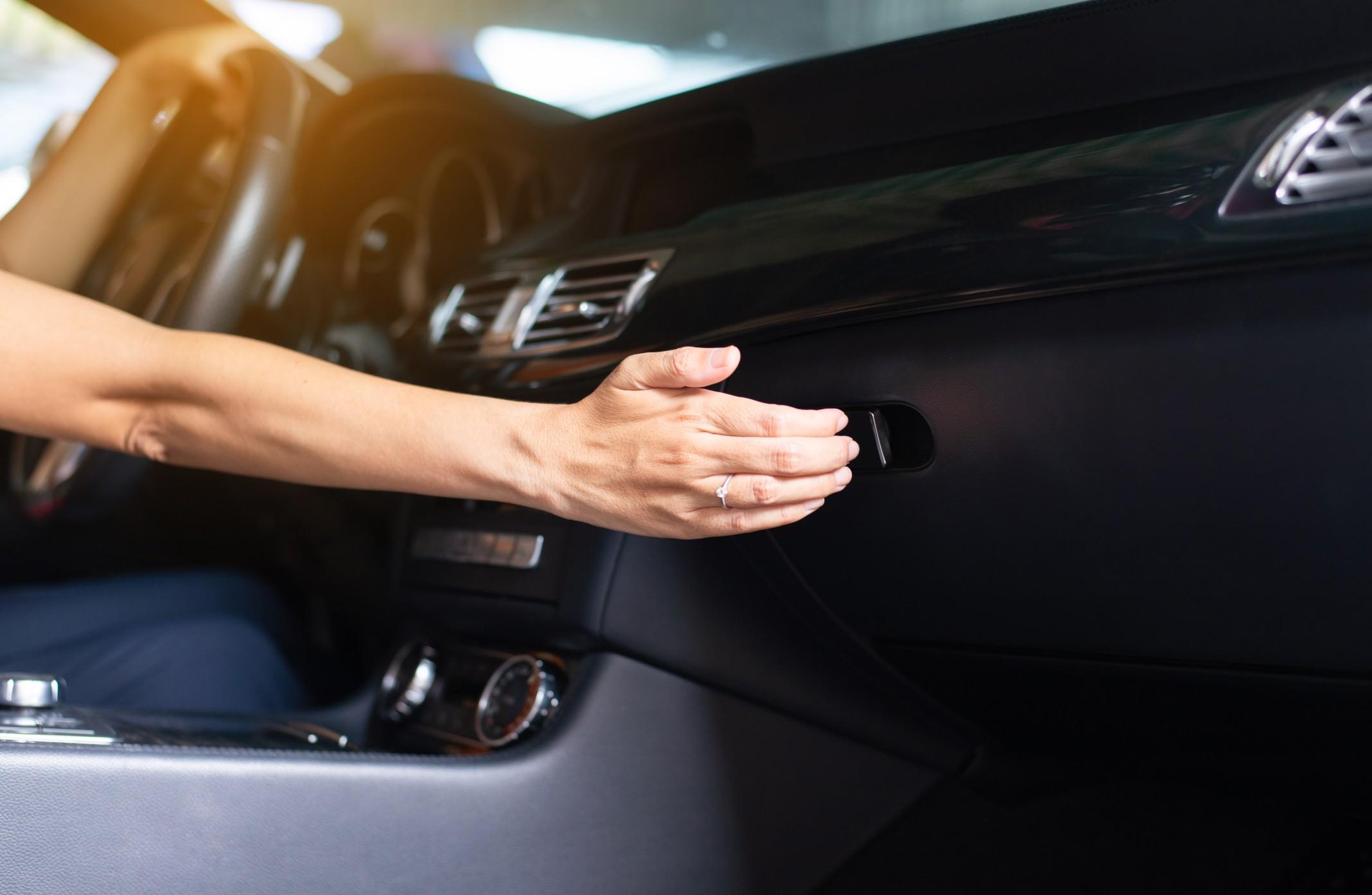 hand reaching for a car's glove box