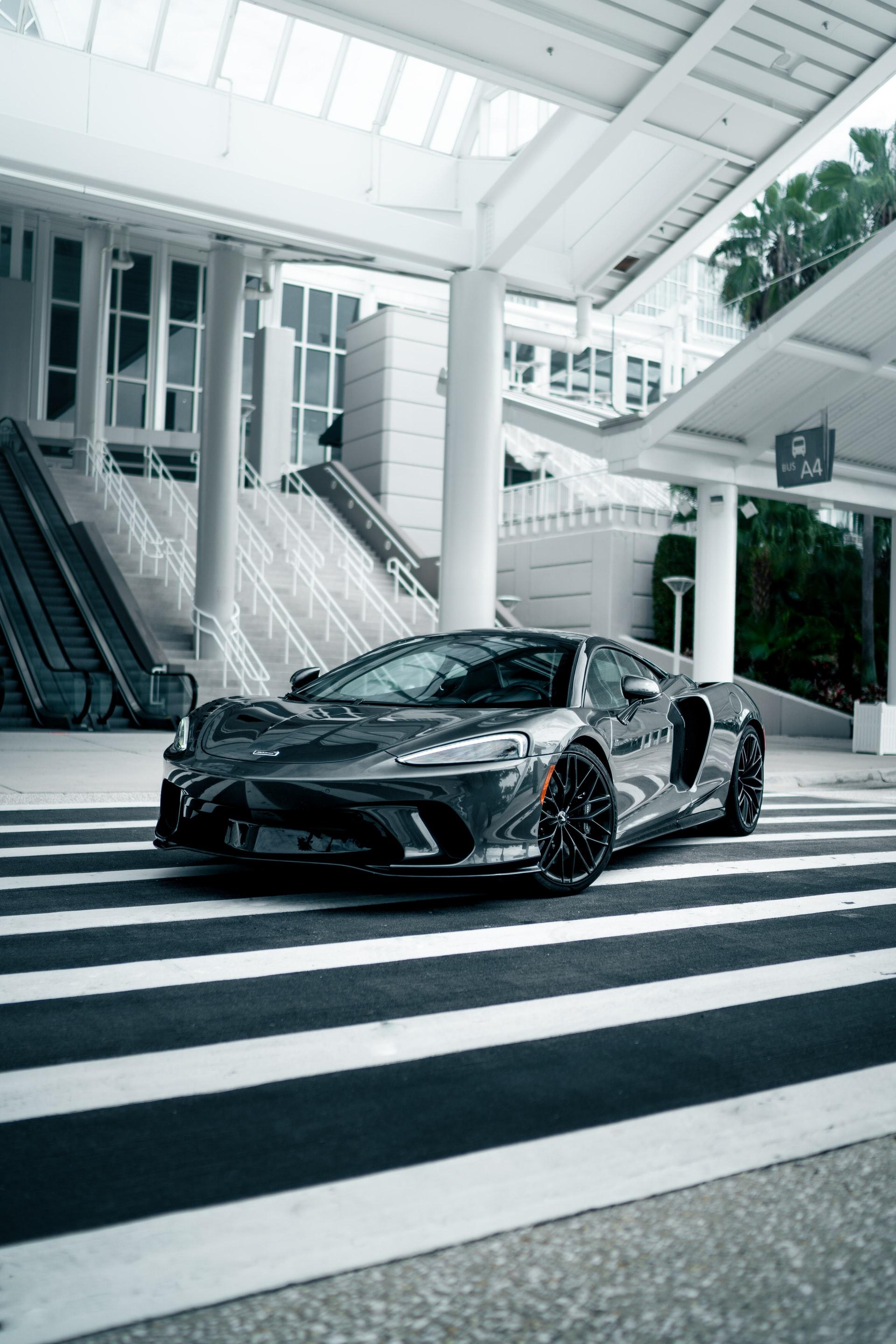 Black McLaren GT parked on a crosswalk in front of a white staircase