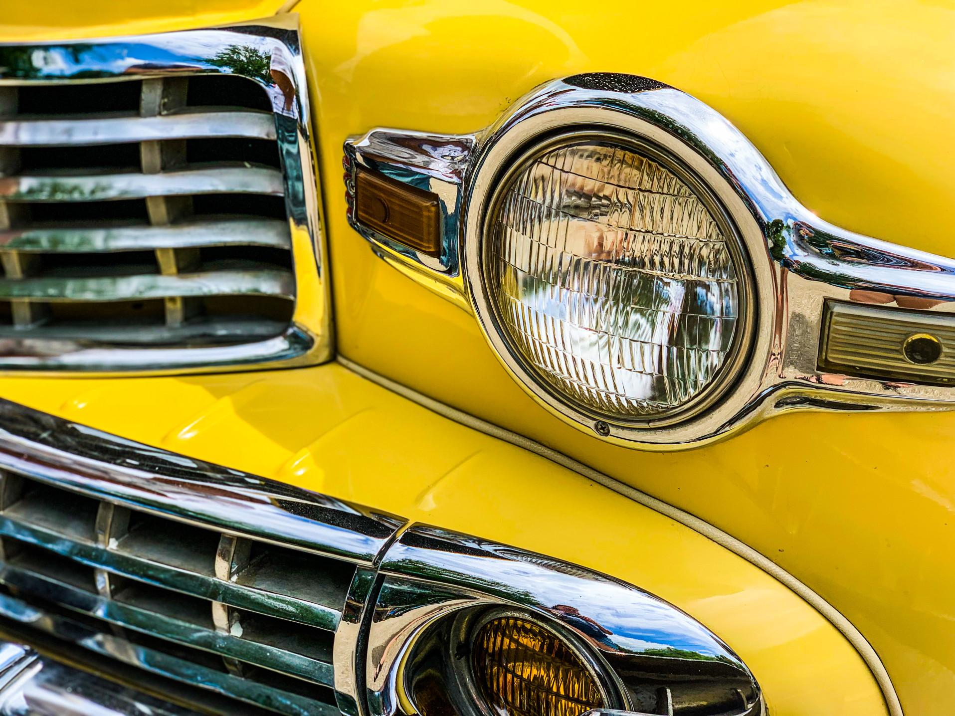 closeup of a headlight of a classic yellow Ford